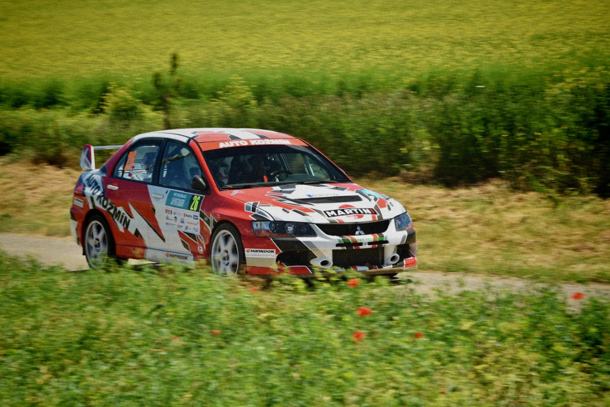 Pilote au volant d'une Ford Fiesta WRC franchissant à grande vitesse une route sinueuse des Vosges