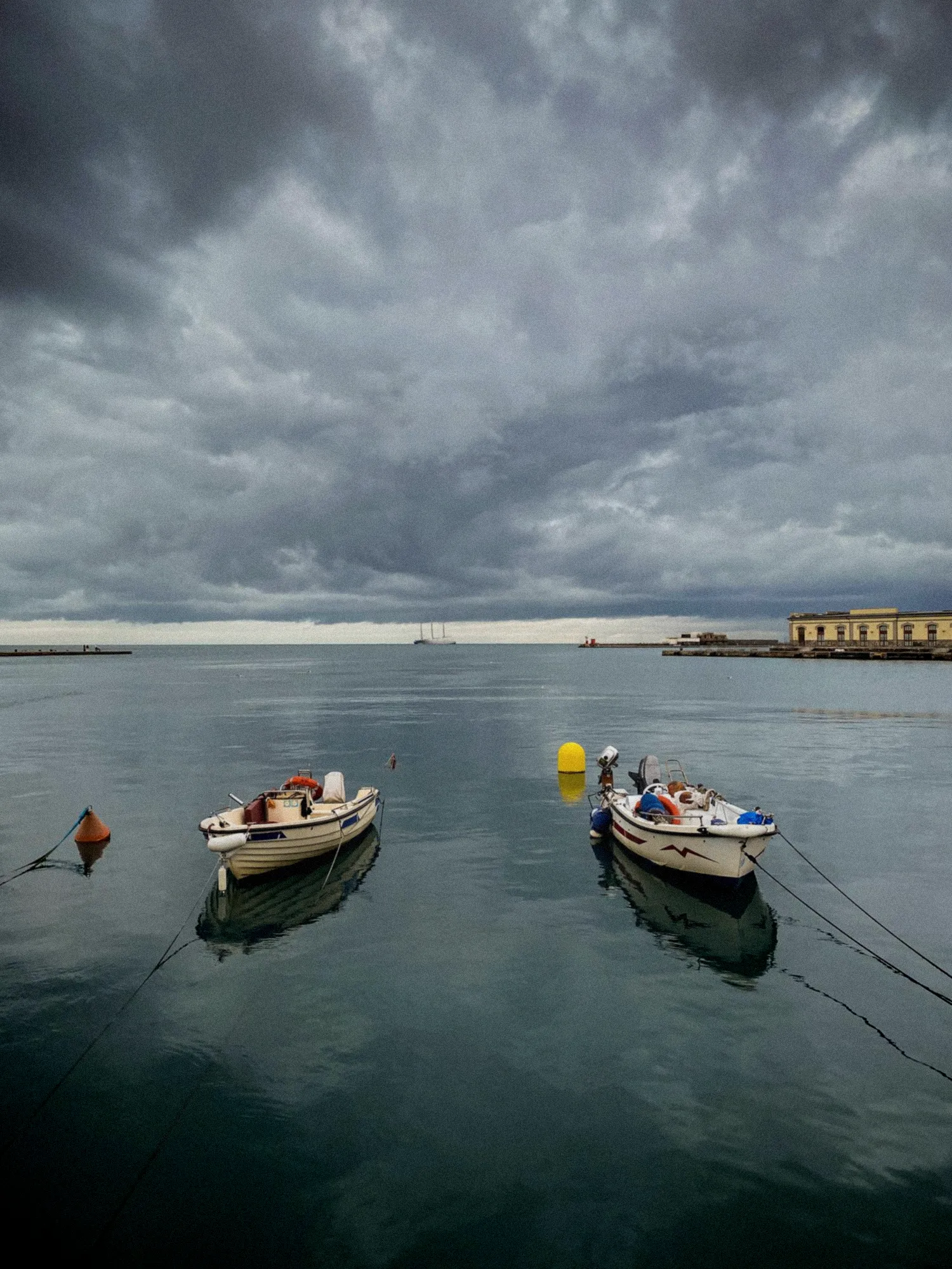 Bateau de pêche ancré dans le port, filets étendus, ciel menaçant et mer agitée