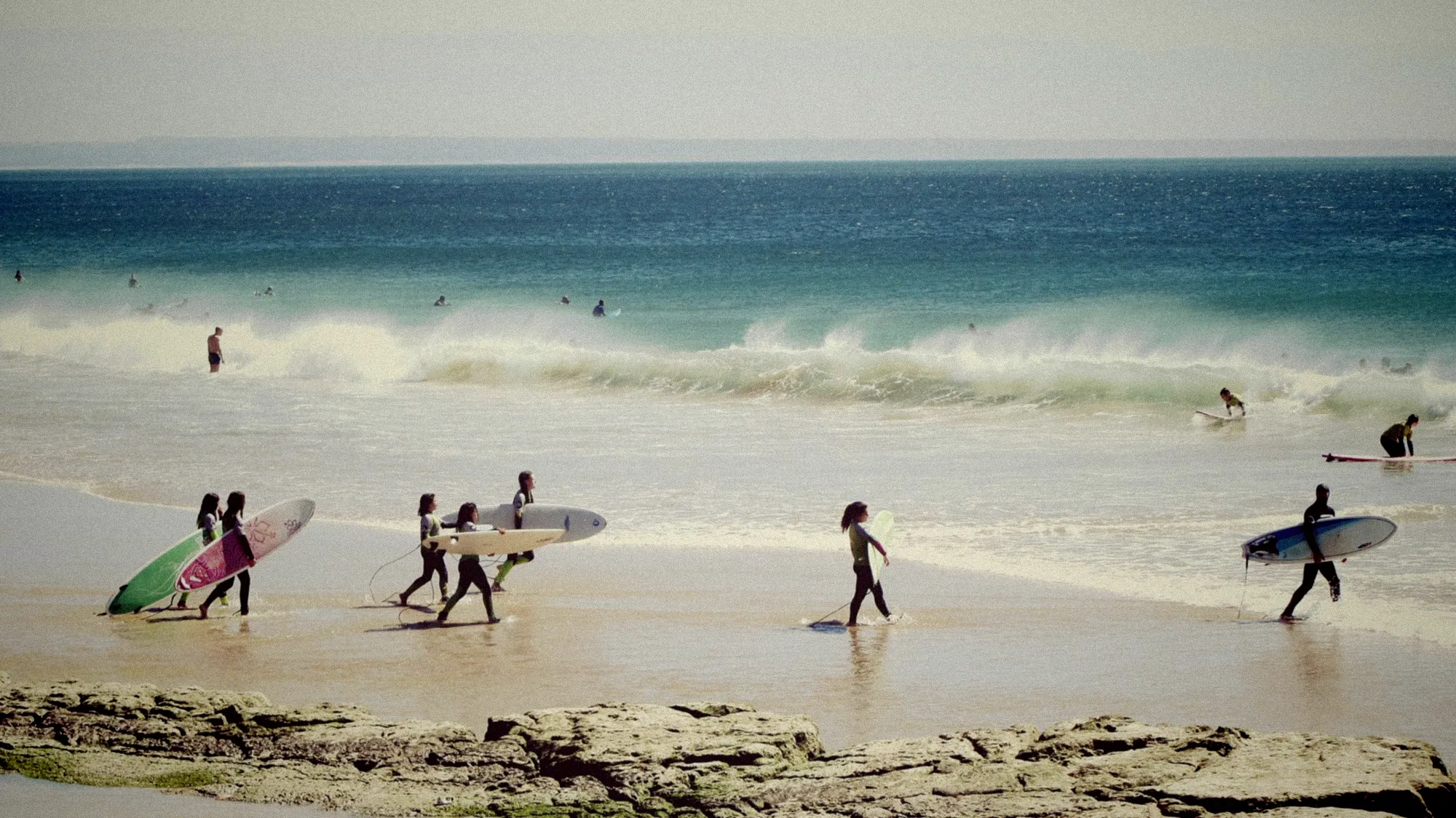Surfeurs en combinaison wetsuit s'élancent dans les vagues turquoise de l'océan Indien