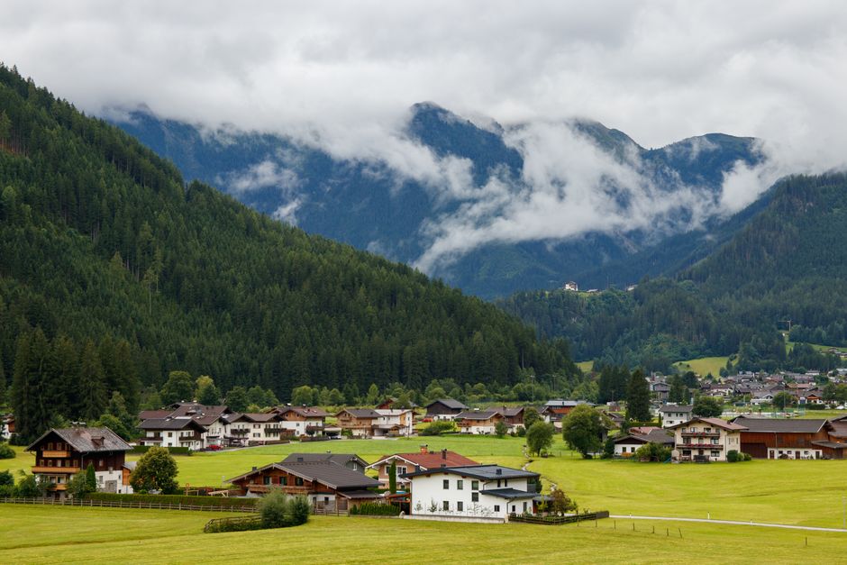 Charming alpine village nestled in lush, misty mountains on a cloudy day.