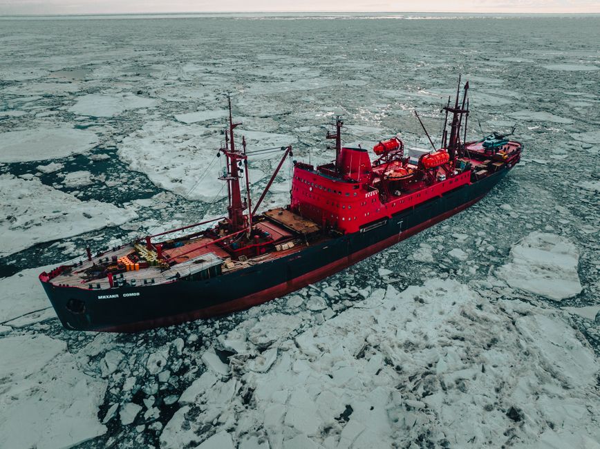 Aerial view of a red icebreaker ship navigating through the icy waters of the Russian Arctic.