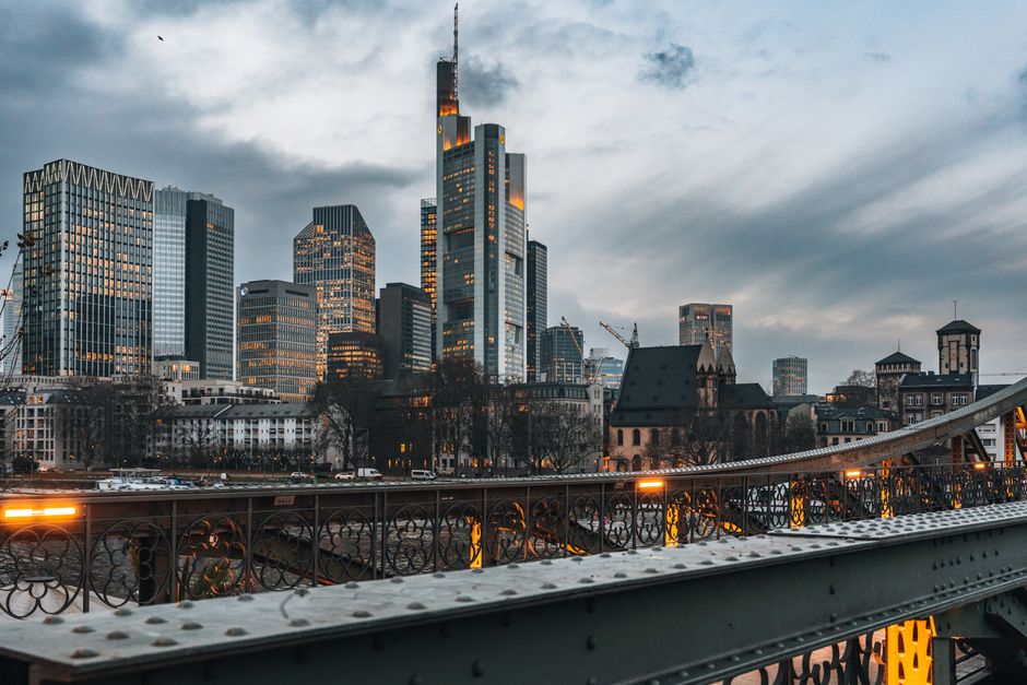 Evening view of Frankfurt skyline with modern skyscrapers and illuminated bridge.