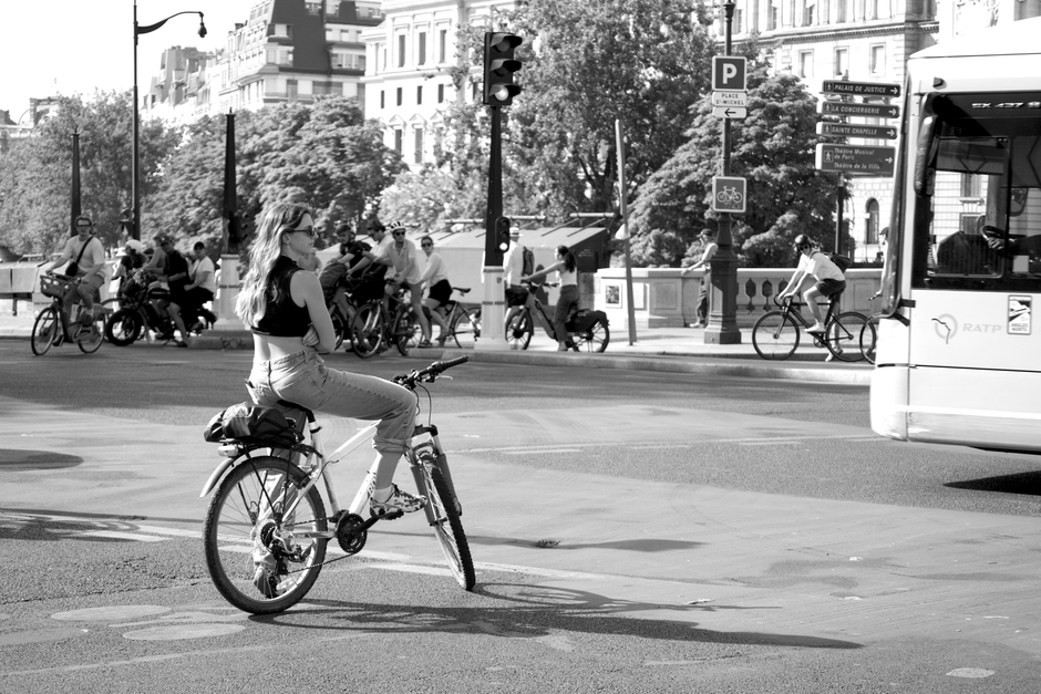 A woman on a bicycle waits at a busy Paris intersection, offering a glimpse of local life.