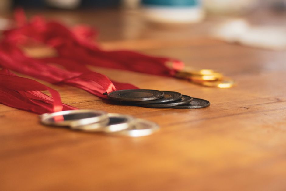 Close-up of gold, silver, and bronze medals with red ribbons on a wooden table.