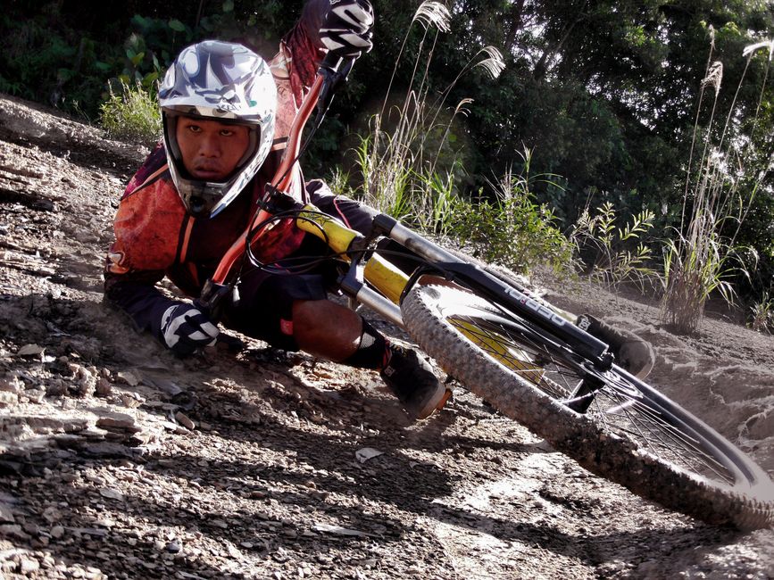 Close-up of a cyclist crashing on a dirt mountain bike track, showing action and speed.