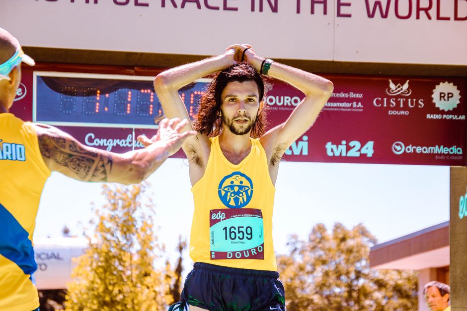 Exhausted marathon runner crossing the finish line triumphantly under sunny skies.
