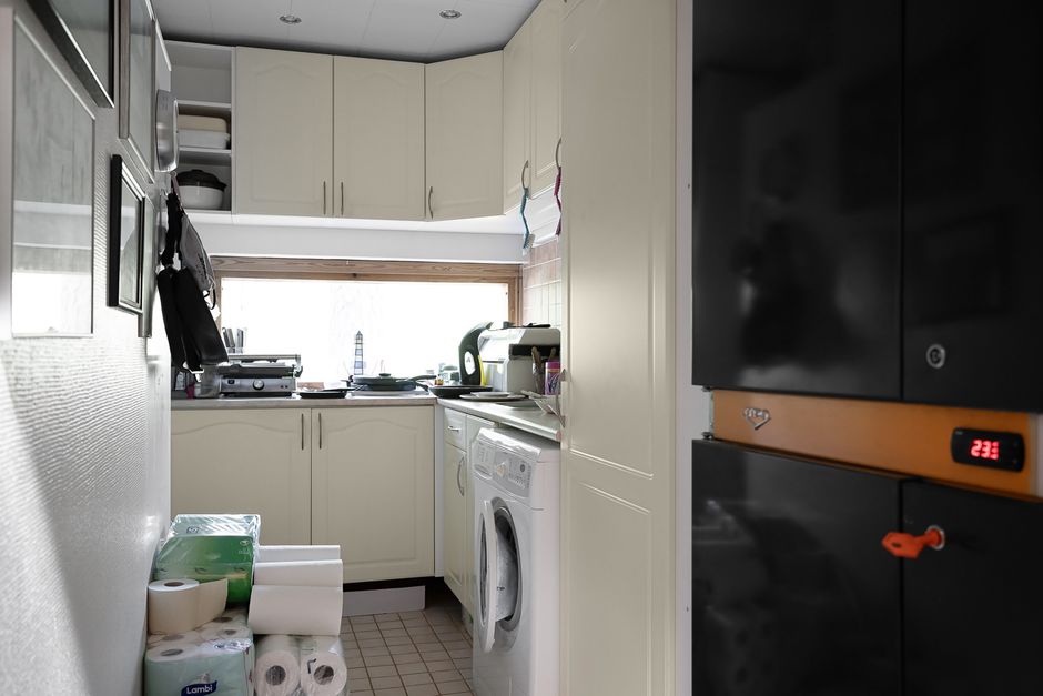 A compact and modern kitchen with laundry appliances, featuring white cabinets and natural light.