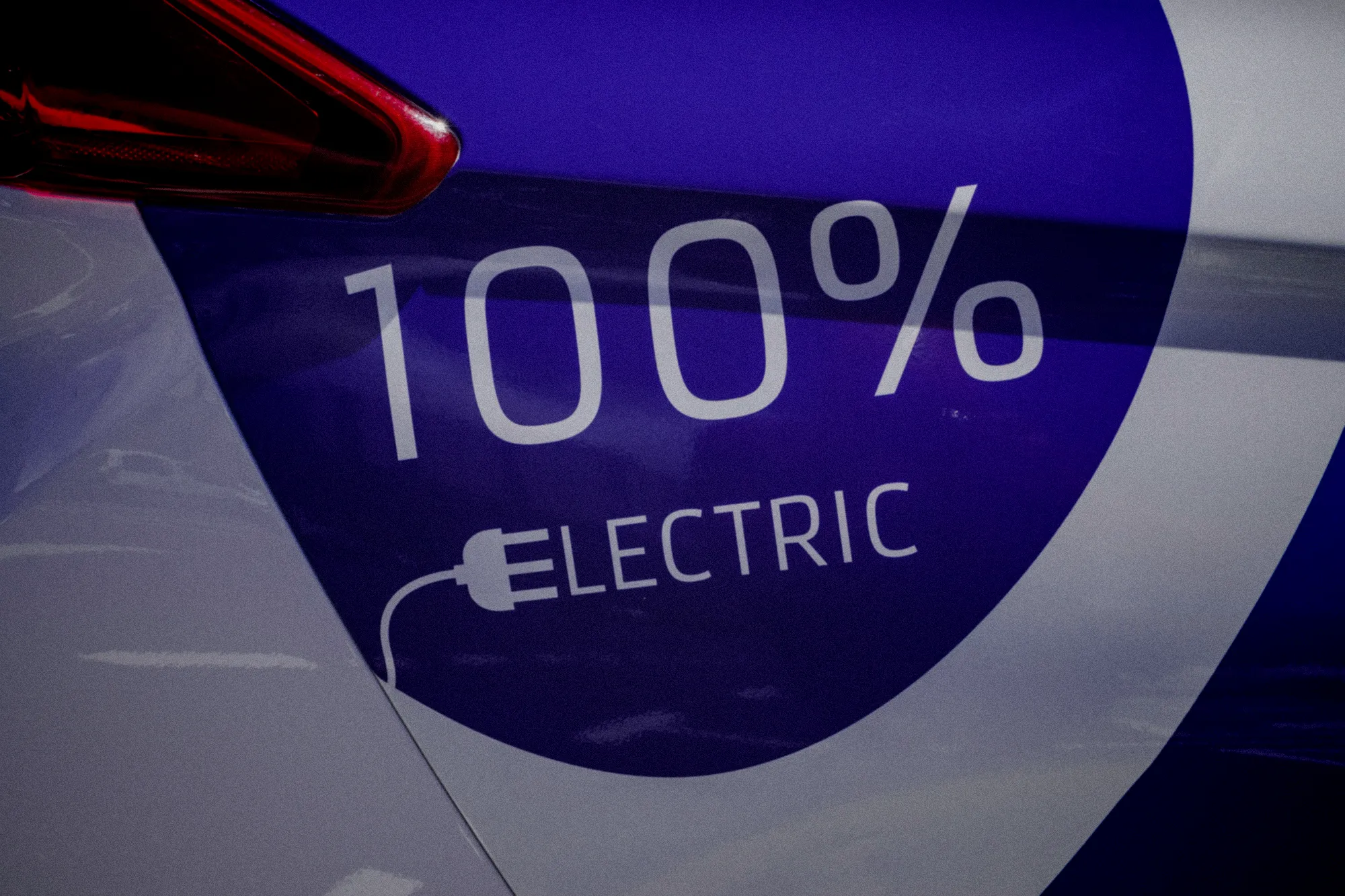 Une voiture électrique rouge recharge à une station publique en centre-ville