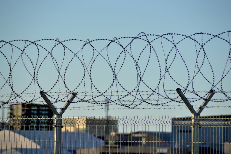 Security fence with barbed wire under clear blue sky in Tallinn, Estonia.