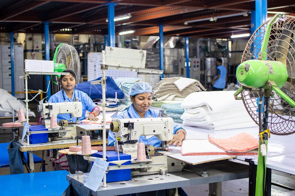 Female workers sew textiles in an Indian factory, showcasing industrial textile production.