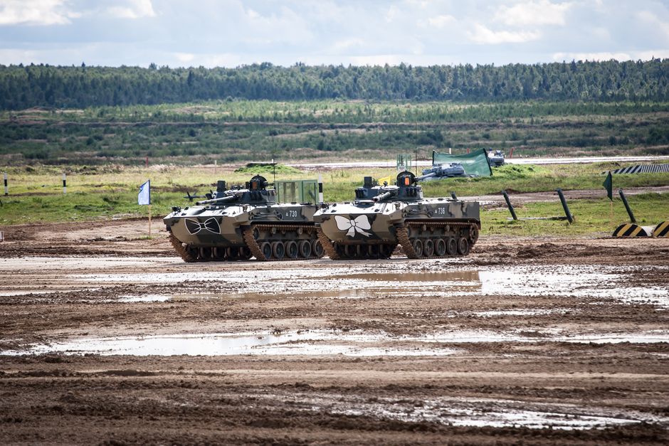 Two military tanks on a muddy field during a cloudy day, showcasing combat readiness.