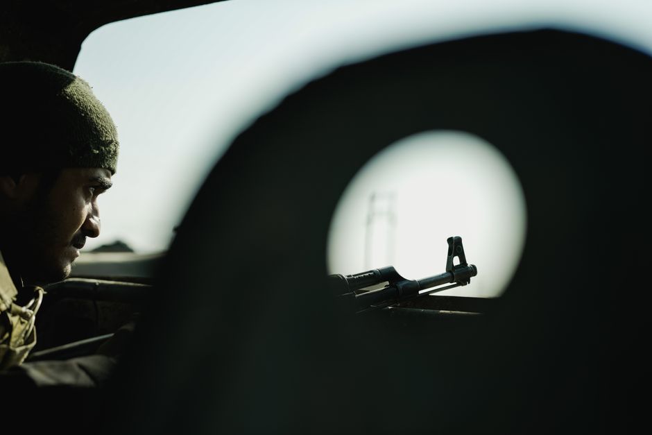 A soldier's profile with a firearm silhouetted against a blurred background, creating a tense atmosphere.