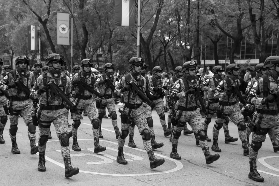 Mexican soldiers marching in formation during a military parade, showcasing discipline and unity.