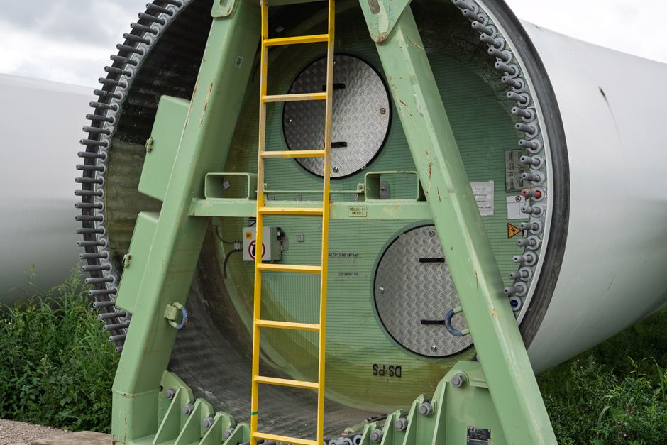Close-up of a wind turbine section with a ladder attached, showcasing industrial design.