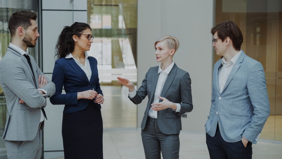 Business professionals in suits discussing strategy in a modern office.