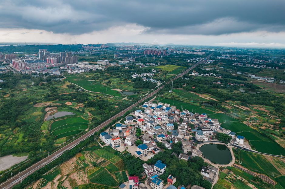Scenic aerial view of suburban and cityscape areas in Jiujiang, Jiangxi, showcasing urban and rural landscapes.