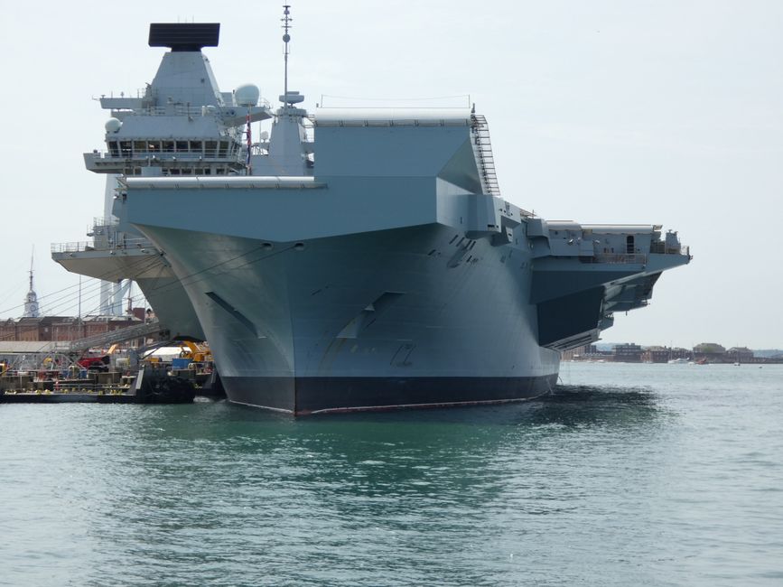 A Royal Navy aircraft carrier docked in Portsmouth, England, showcasing naval engineering.