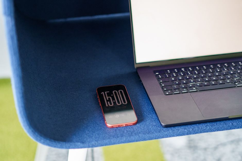 A minimalist workspace featuring a laptop and smartphone on a stylish blue chair.