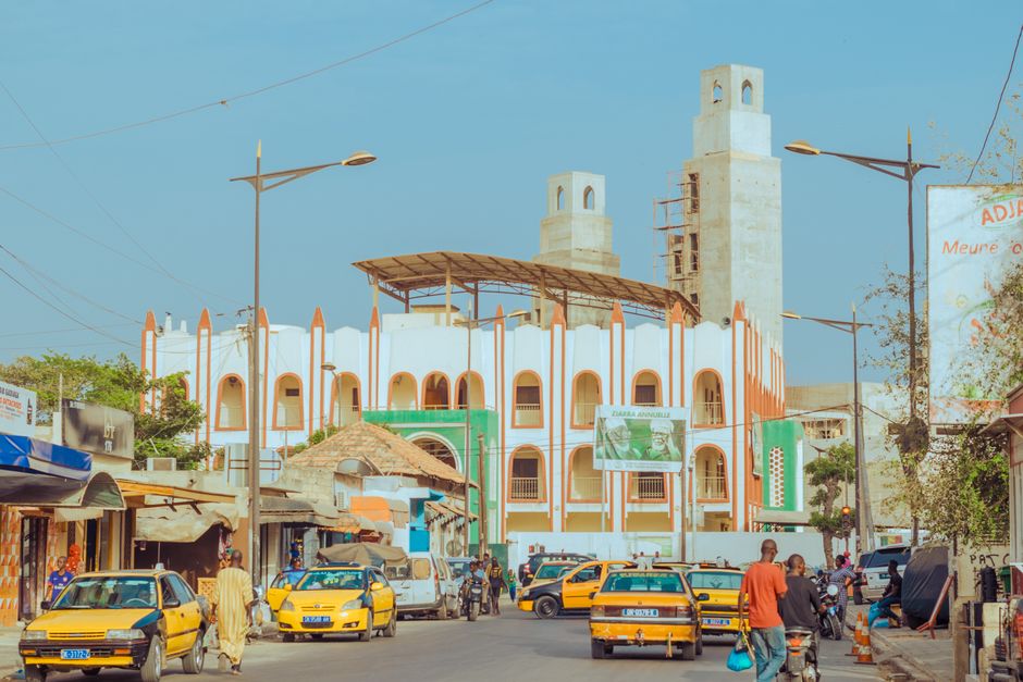 A vibrant street scene featuring an Islamic mosque with distinct architecture under a clear blue sky.