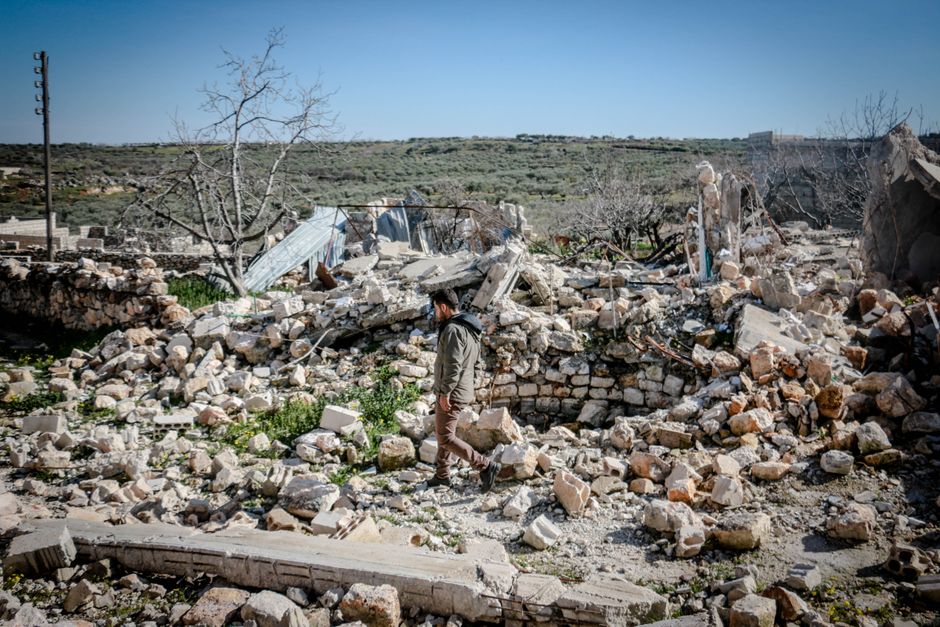 A man navigates through rubble after an earthquake in rural Idlib, Syria.
