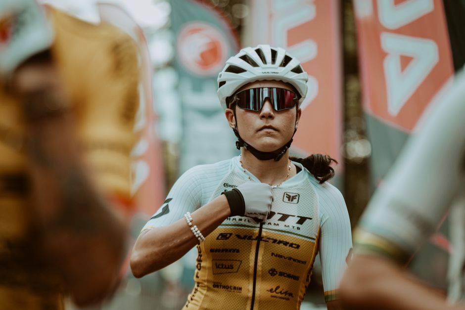 A determined cyclist adjusts her gear, preparing for a race. Captured in a vibrant outdoor setting.