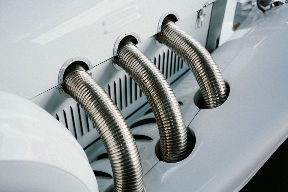 Close-up of a vintage car's chrome exhaust pipes, showcasing elegance and mechanical design.