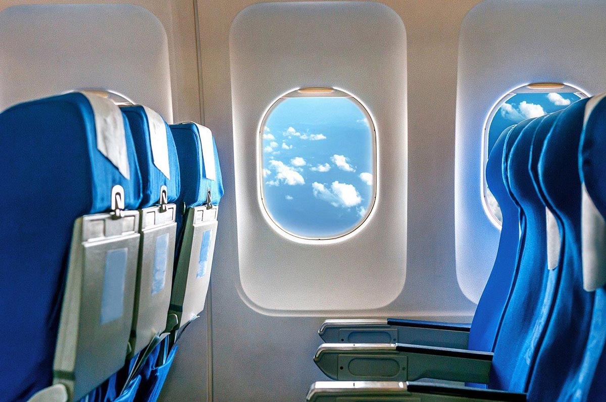 Cabine moderne d’avion de ligne avec rangées de sièges et hublots donnant sur le ciel