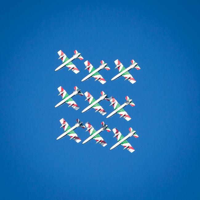 Fighter jets in a precise formation fly against a vibrant blue sky during an airshow.