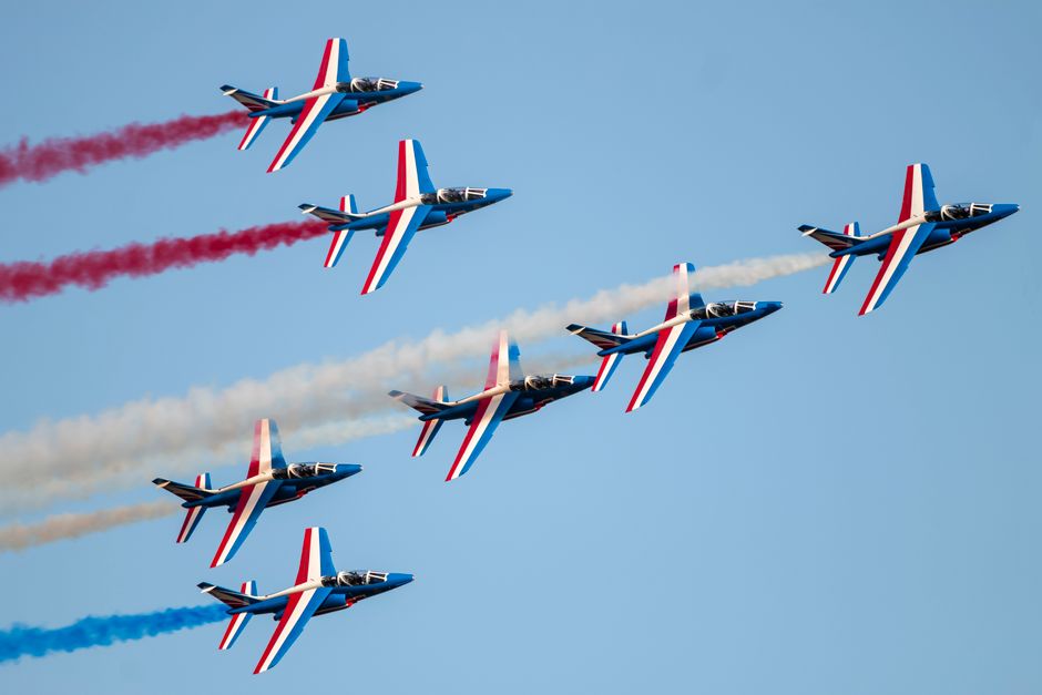 Patrouille de France flyover showcasing aerobatic skills at Bucharest airshow, clear blue skies.