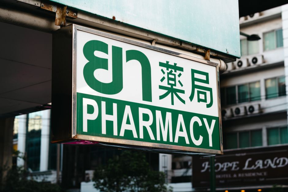 Outdoor street view of a pharmacy sign in Bangkok, Thailand.
