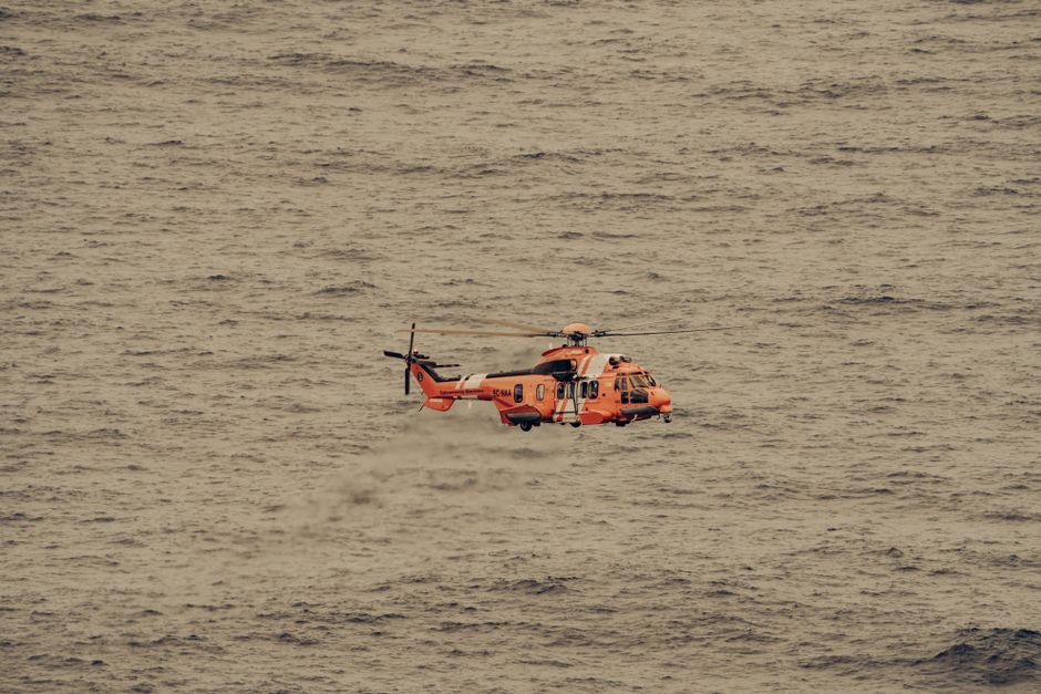An aerial view of a rescue helicopter flying over the vast ocean, captured mid-flight.