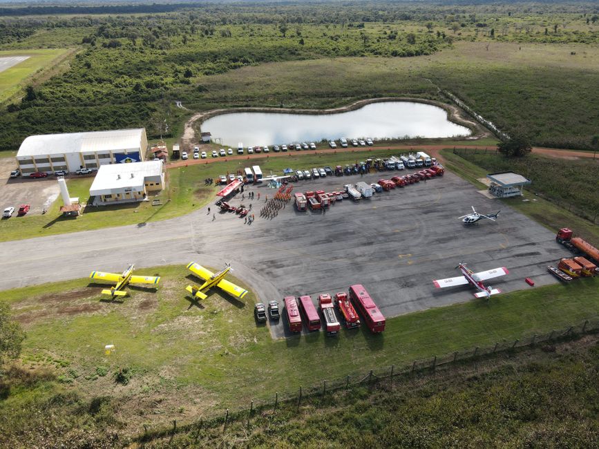 Aerial shot of firefighting base with planes, trucks, and personnel in a rural area of Brazil.