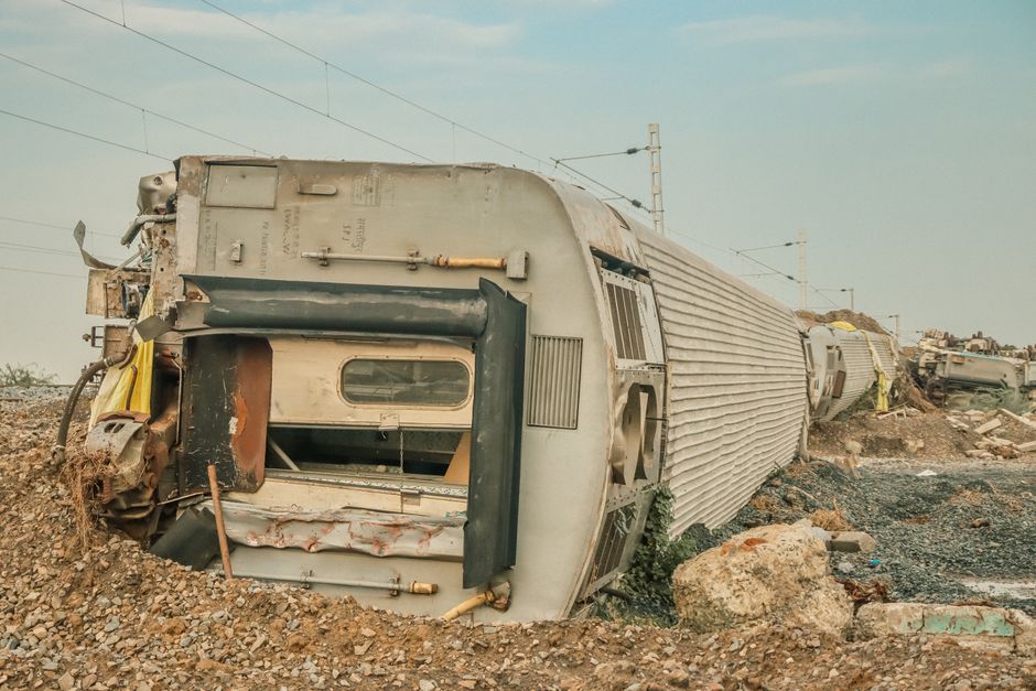 Train déraillé couché sur le flanc aux abords d'une voie ferrée.