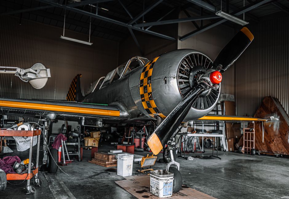 Un avion à réaction gris aux hélices stationnée dans un hangar moderne pour maintenance