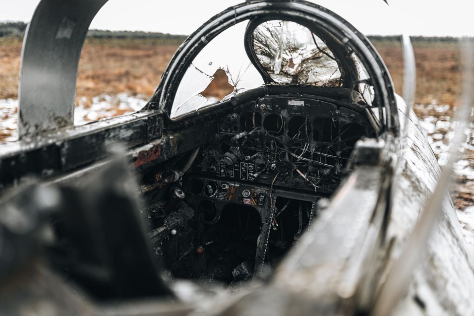 Cockpit détruit d'une épave d'avion dans un champ enneigé.