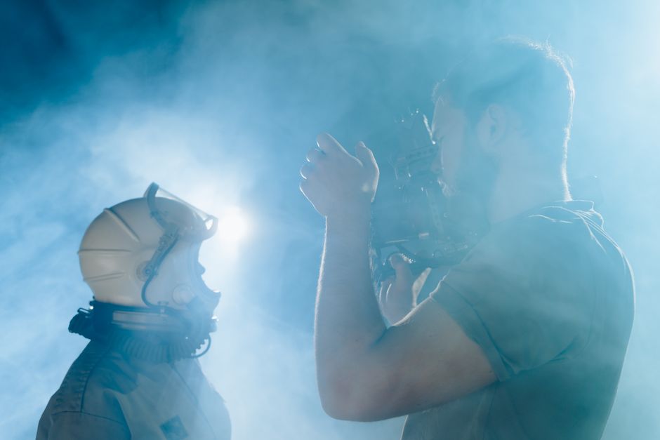 Un astronaute et un cameraman filment dans une atmosphère enfumée.