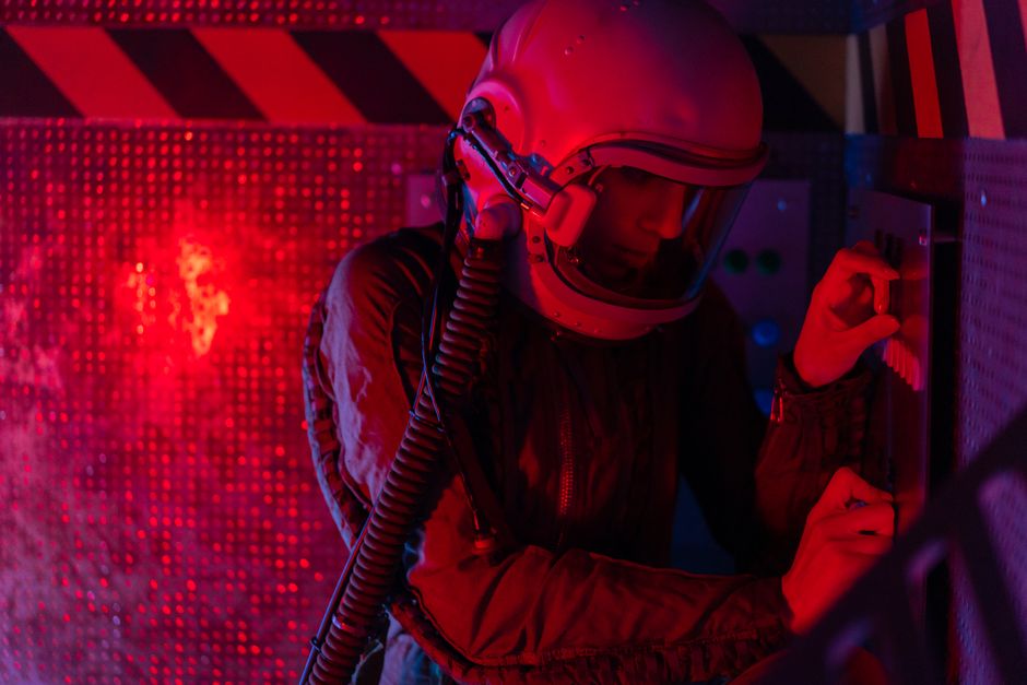 Une astronaute manipule un panneau de contrôle sous éclairage rouge