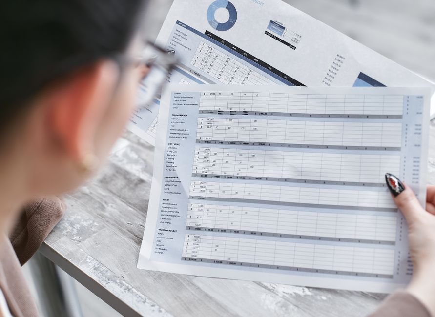 Une femme consulte des tableaux financiers et des graphiques sur son bureau.