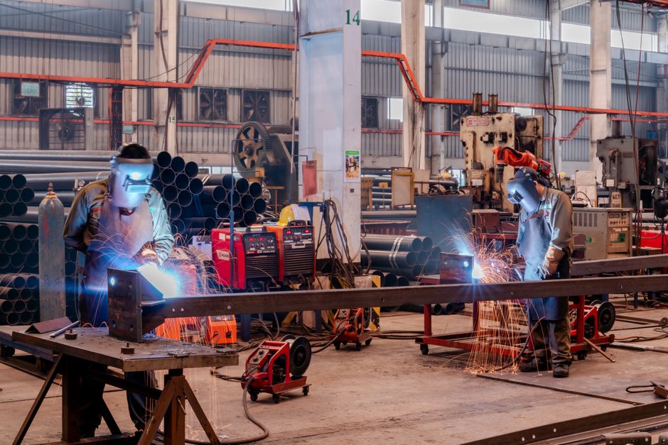 Deux soudeurs en équipement de protection travaillant dans un atelier d'usine.