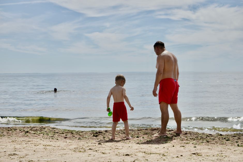 Un père et son fils marchent ensemble sur une plage ensoleillée
