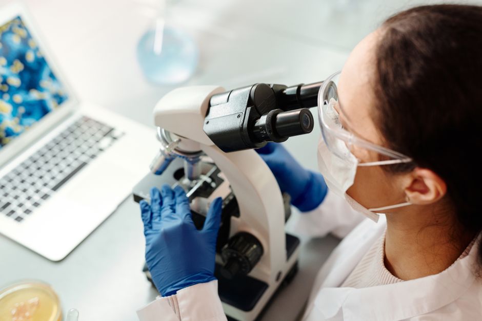 Chercheur en tenue de protection examine des échantillons au microscope en laboratoire