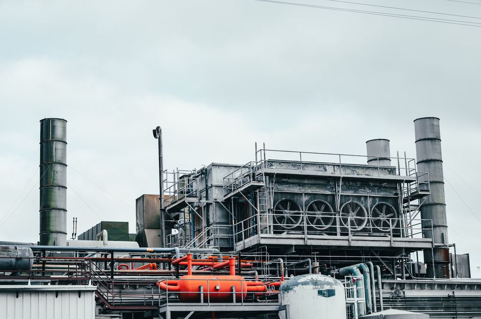 Usine avec tuyauteries métalliques et équipements industriels sous ciel nuageux