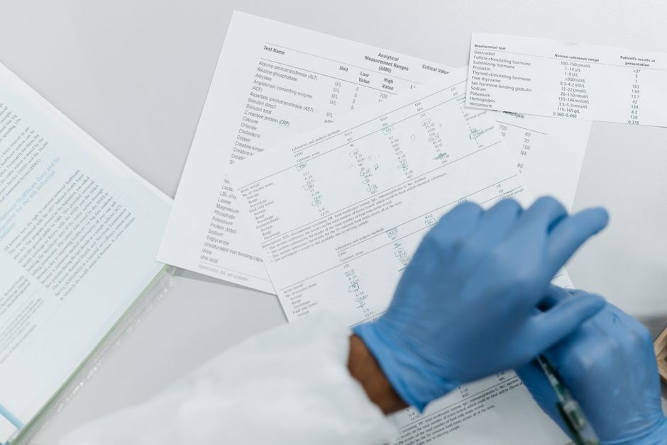 Des mains gantées examinent des résultats d'analyses imprimés sur une surface blanche.