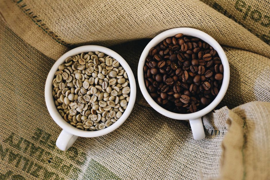 Grains de café crus et torréfiés disposés dans des tasses