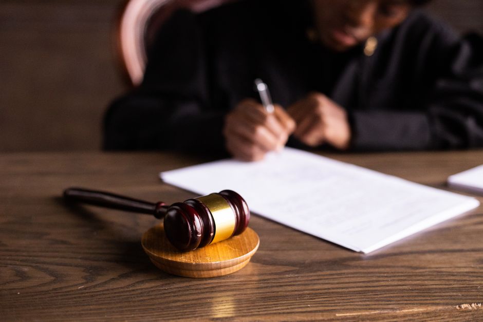 Un juge signe des documents à son bureau avec son marteau de justice.