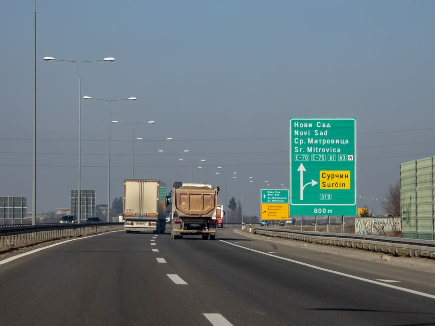 Camions circulant sur une autoroute européenne avec panneaux de signalisation.