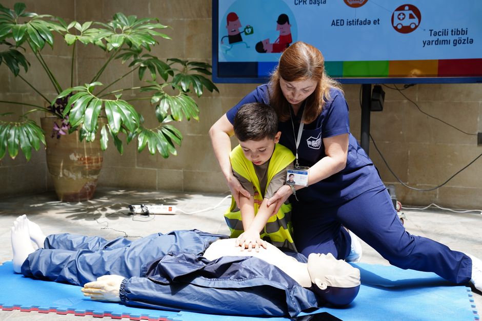 Une infirmière guide un enfant lors d'un entraînement aux gestes de secours.