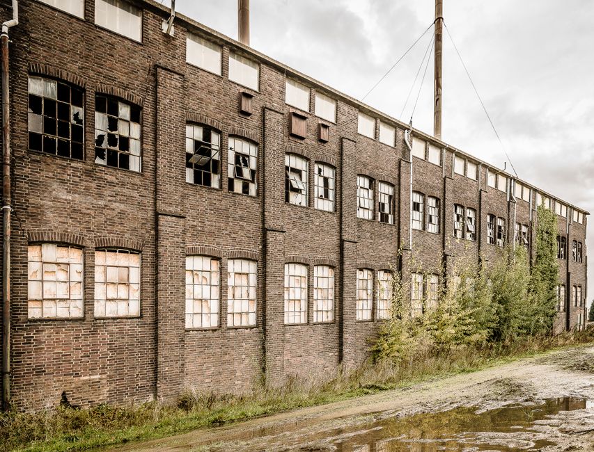 Bâtiment industriel abandonné aux façades dégradées et fenêtres cassées