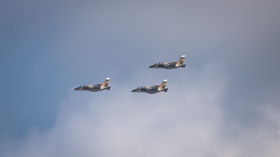 Trois avions de chasse volent en formation dans un ciel bleu dégagé.