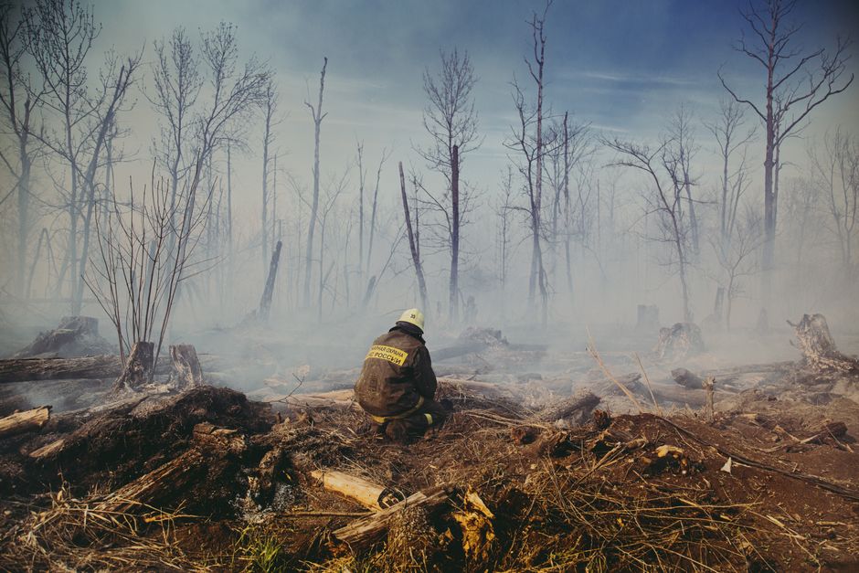 Pompier assis dans les décombres enfumés d'un incendie de forêt